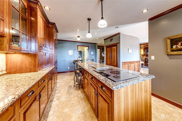 kitchen featuring a center island, decorative light fixtures, light stone countertops, black electric stovetop, and ornamental molding