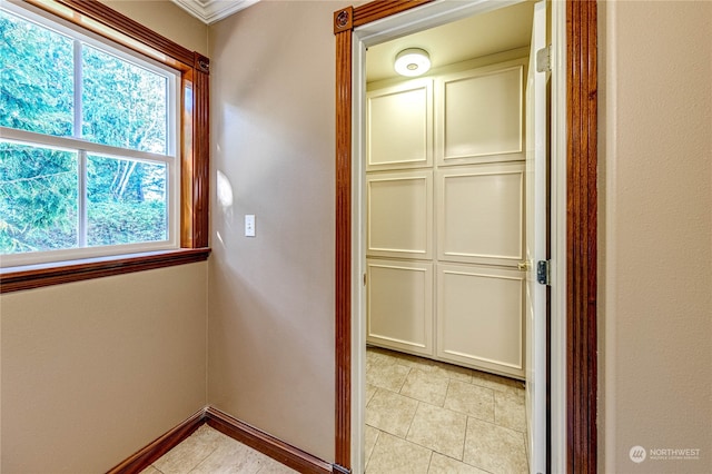 hallway featuring ornamental molding and light tile patterned floors