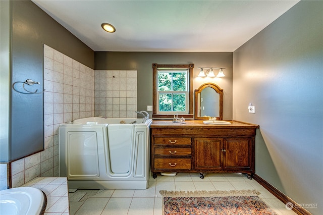 bathroom featuring vanity, a bath, washer and dryer, and tile patterned floors