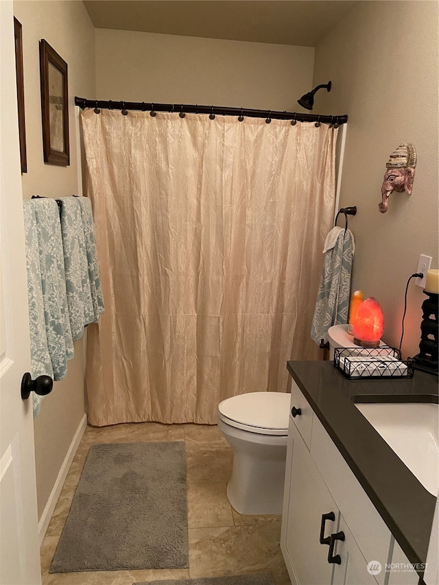 bathroom with toilet, vanity, and tile patterned floors