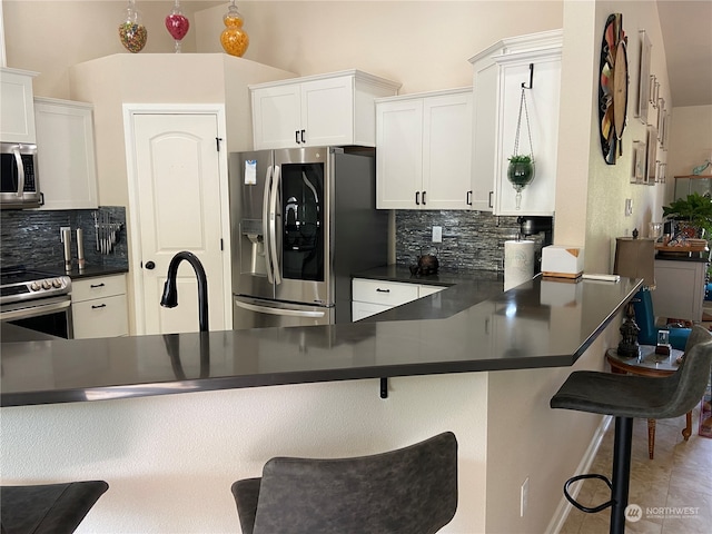 kitchen with tasteful backsplash, stainless steel appliances, white cabinetry, a breakfast bar area, and kitchen peninsula