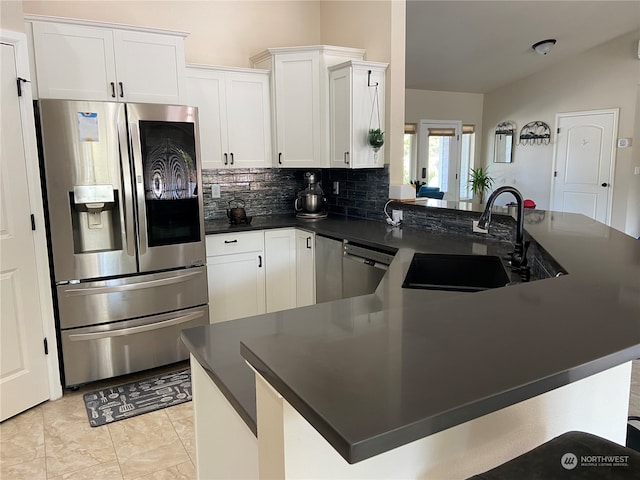 kitchen with tasteful backsplash, appliances with stainless steel finishes, sink, vaulted ceiling, and white cabinets