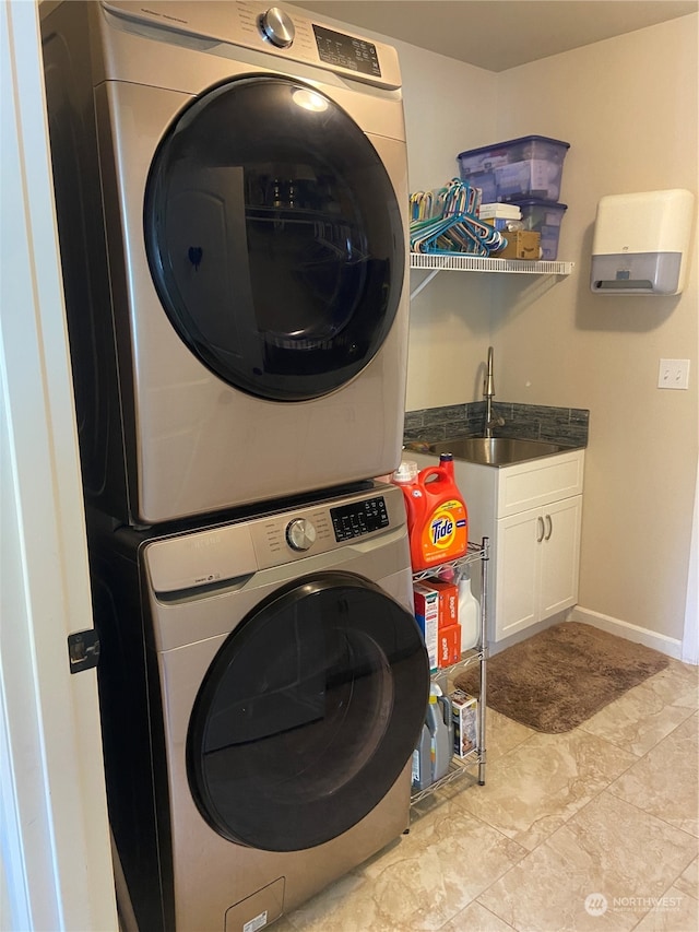 clothes washing area with stacked washer and clothes dryer, cabinets, sink, and light tile patterned floors