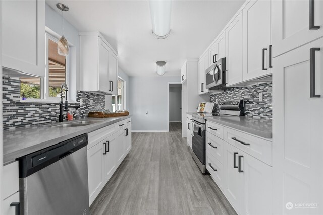 kitchen with light wood-type flooring, white cabinetry, decorative light fixtures, stainless steel appliances, and sink