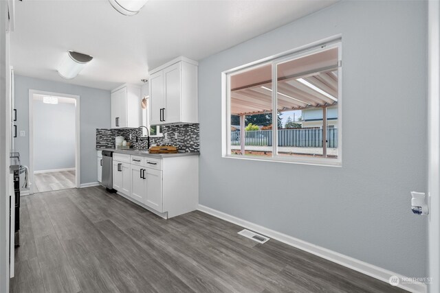 kitchen with hardwood / wood-style floors, white cabinetry, sink, decorative backsplash, and stainless steel dishwasher