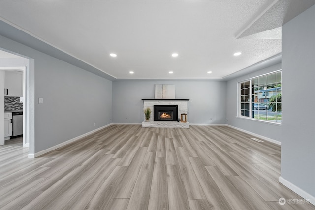 unfurnished living room with light wood-type flooring and a textured ceiling