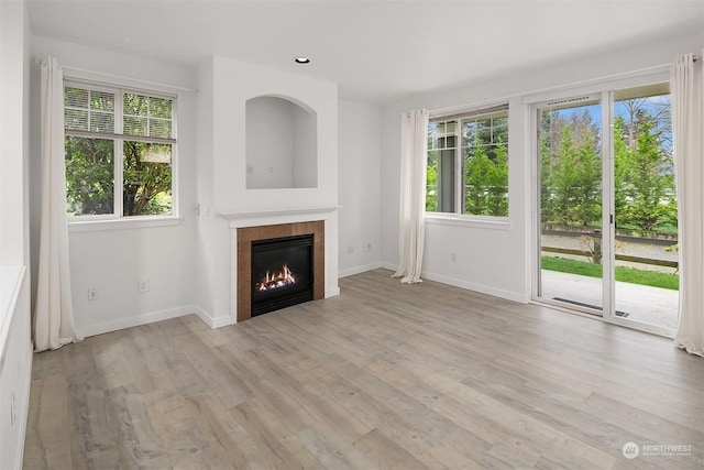 unfurnished living room with plenty of natural light, a fireplace, and light hardwood / wood-style flooring