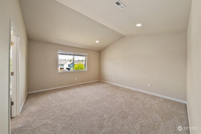 carpeted spare room featuring vaulted ceiling