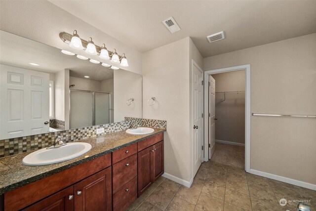 bathroom featuring a shower with door, vanity, tile patterned floors, and tasteful backsplash