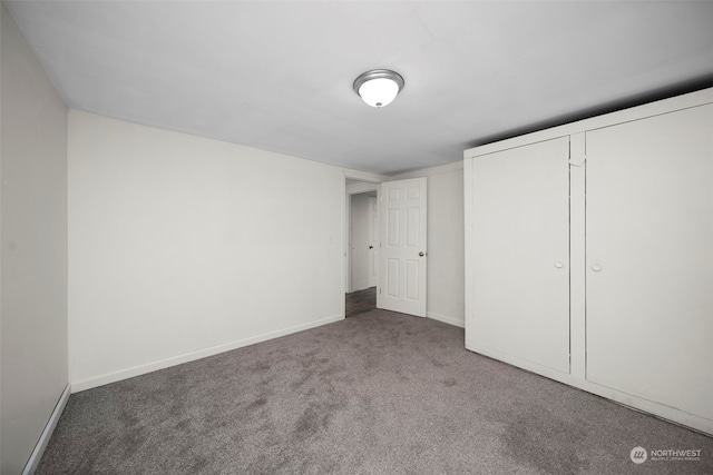 unfurnished bedroom featuring a closet and dark carpet