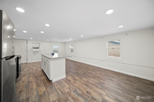 kitchen with white cabinets, dark hardwood / wood-style flooring, a center island, and stainless steel refrigerator