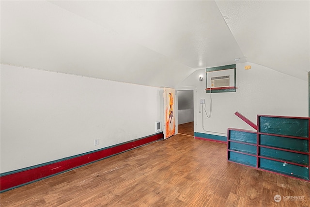 bonus room with hardwood / wood-style flooring, a wall mounted air conditioner, and vaulted ceiling