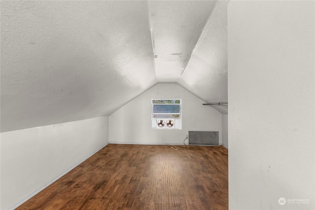 additional living space featuring lofted ceiling, wood-type flooring, and a textured ceiling