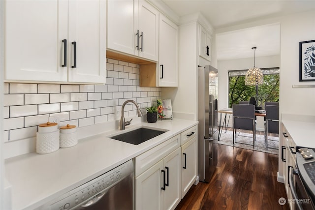 kitchen with dark hardwood / wood-style floors, hanging light fixtures, stainless steel appliances, sink, and white cabinets