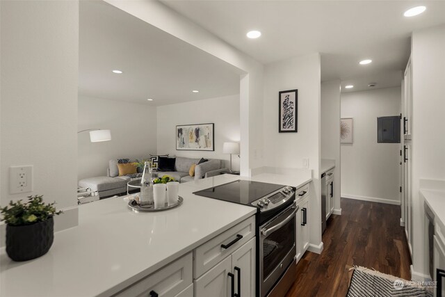 kitchen with dark wood-type flooring, white cabinets, electric range, and electric panel