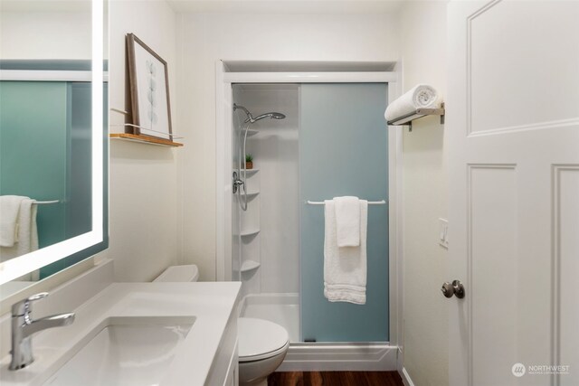 bathroom featuring vanity, toilet, hardwood / wood-style flooring, and a shower with shower door