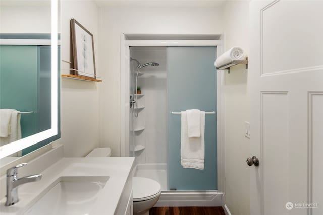 full bathroom with a stall shower, toilet, vanity, and wood finished floors