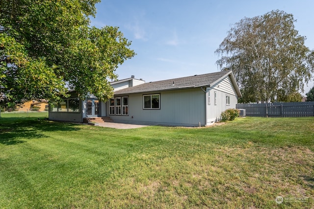 rear view of property with central AC and a yard