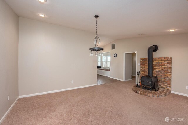 unfurnished living room with a wood stove, carpet floors, and lofted ceiling