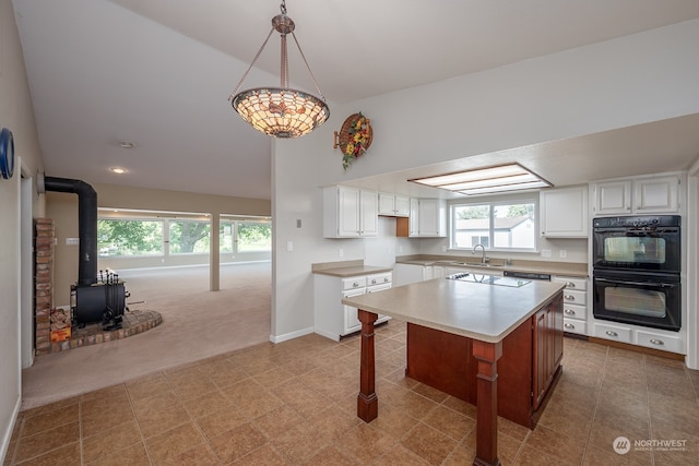 kitchen featuring a center island, light colored carpet, a wood stove, white cabinetry, and double oven