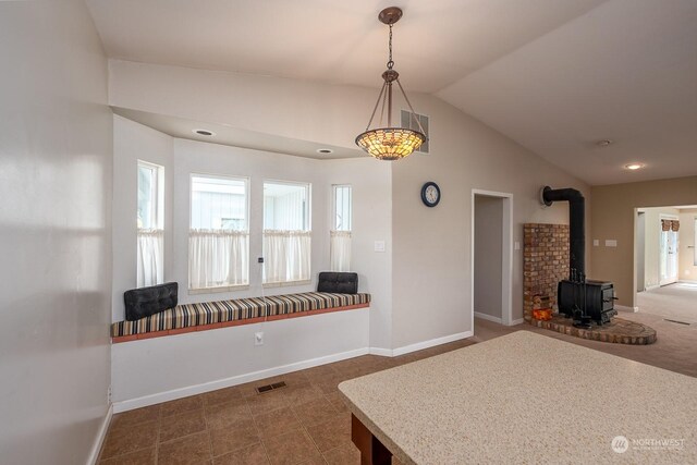 carpeted dining space featuring lofted ceiling and a wood stove