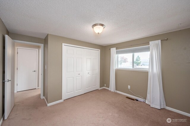 unfurnished bedroom featuring a closet, light colored carpet, and a textured ceiling