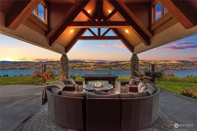 patio terrace at dusk with a water and mountain view and an outdoor living space with a fire pit