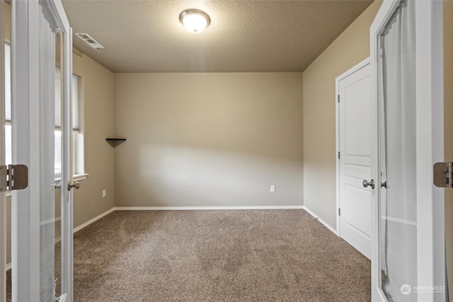 carpeted empty room with a textured ceiling