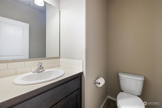 bathroom with backsplash, vanity, and toilet