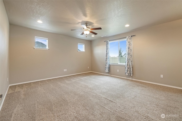 carpeted spare room featuring a textured ceiling, ceiling fan, and plenty of natural light