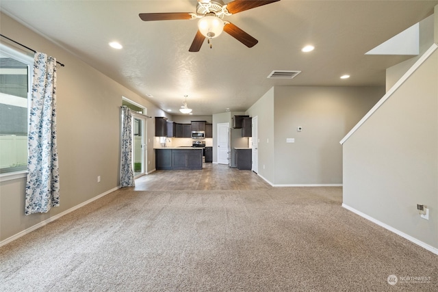 unfurnished living room with carpet floors, sink, and ceiling fan