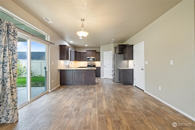 kitchen with appliances with stainless steel finishes, hanging light fixtures, wood-type flooring, dark brown cabinets, and sink