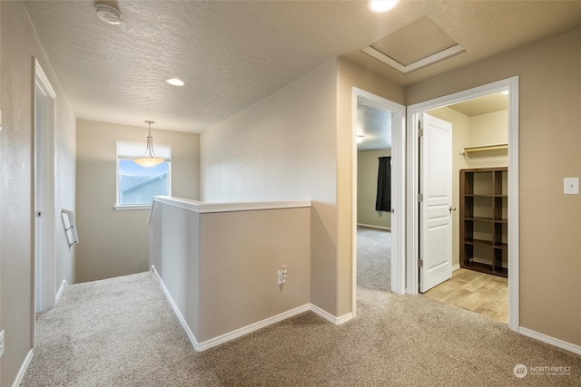 corridor with a textured ceiling and light colored carpet