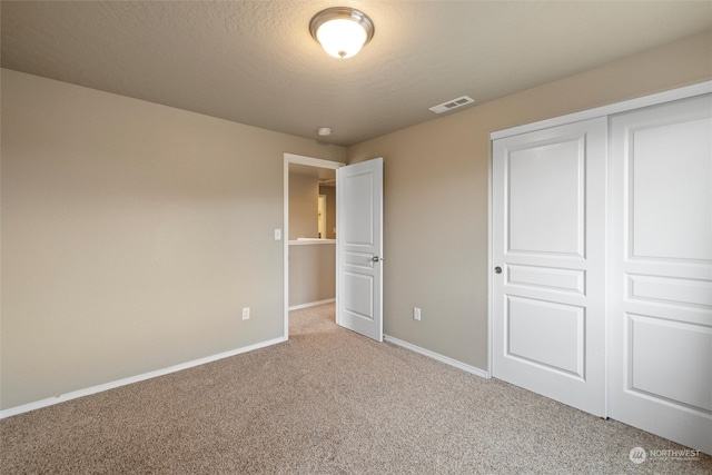 unfurnished bedroom with light carpet, a textured ceiling, and a closet