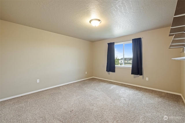 carpeted empty room featuring a textured ceiling