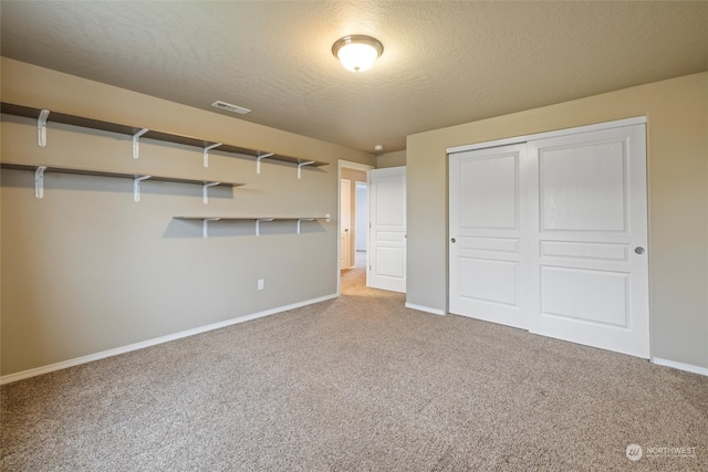 interior space featuring light carpet, a closet, and a textured ceiling