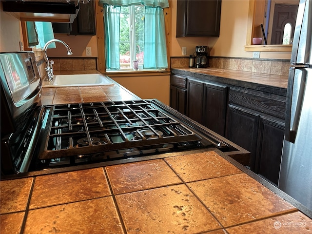 kitchen with stainless steel fridge, dark brown cabinetry, and sink