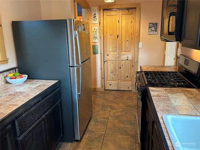 kitchen with tile counters, sink, and appliances with stainless steel finishes