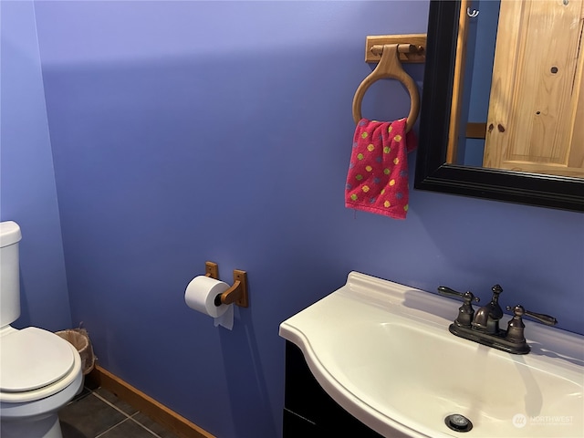 bathroom with toilet, sink, and tile patterned flooring