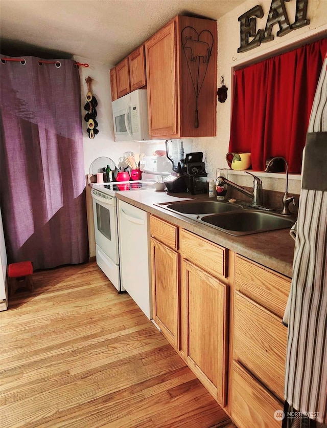 kitchen featuring light wood-type flooring, white appliances, sink, and a textured ceiling