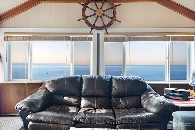 living room with a water view, wooden walls, and vaulted ceiling