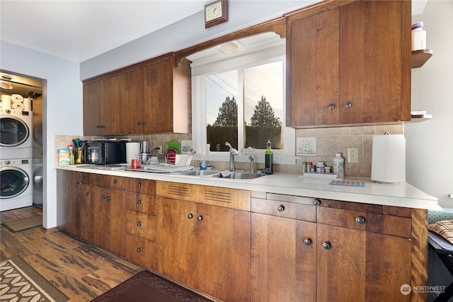 kitchen with stacked washer / drying machine, sink, decorative backsplash, and dark hardwood / wood-style floors