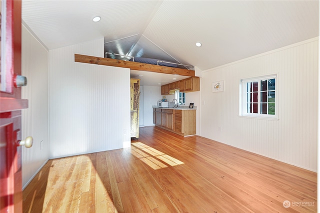 unfurnished living room with sink, light hardwood / wood-style floors, crown molding, and vaulted ceiling