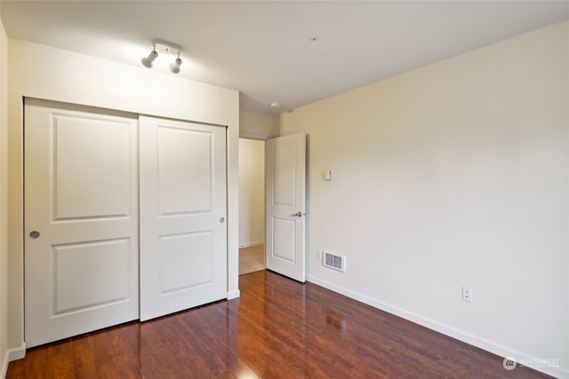 unfurnished bedroom with a closet and dark hardwood / wood-style floors