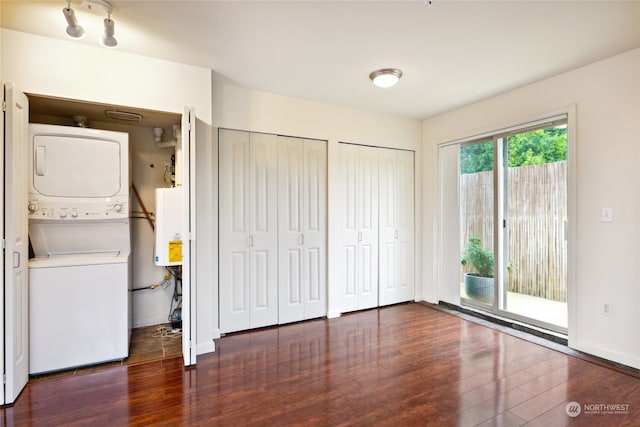 interior space with stacked washer and dryer, dark wood-type flooring, access to outside, and multiple closets