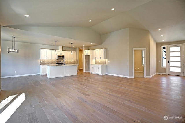 unfurnished living room featuring high vaulted ceiling and light hardwood / wood-style flooring