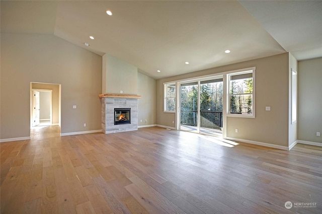 unfurnished living room with high vaulted ceiling, a fireplace, and light hardwood / wood-style floors