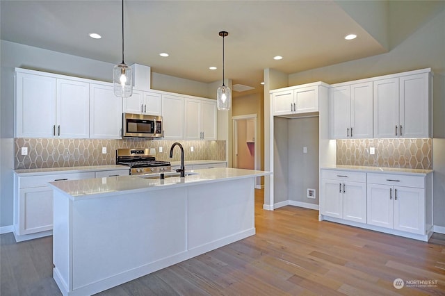 kitchen with stainless steel appliances, white cabinetry, sink, and pendant lighting