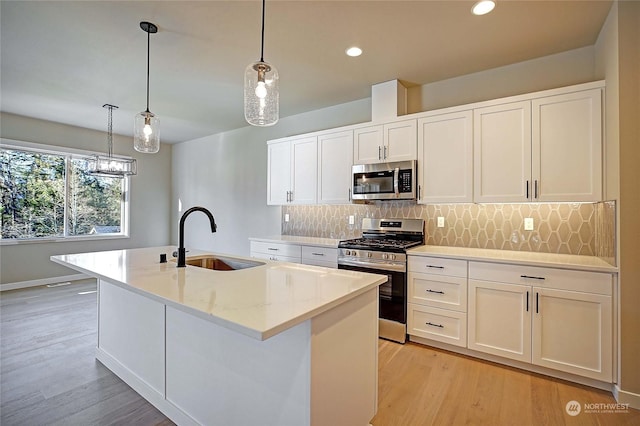 kitchen featuring stainless steel appliances, sink, a center island with sink, and white cabinets