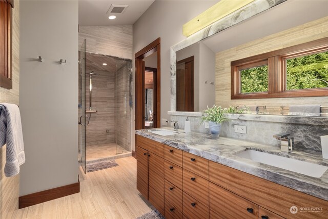 bathroom with hardwood / wood-style floors, vanity, tasteful backsplash, lofted ceiling, and a shower with shower door